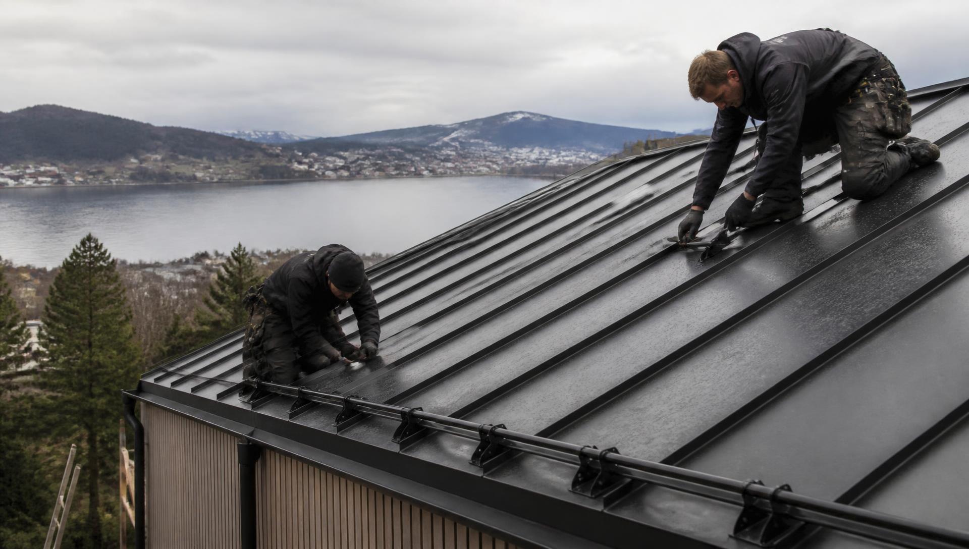 Blikkenslagere legger båndtekket metalltak på bolig med utsikt over fjorden i Bergen